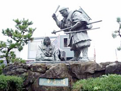 義経と弁慶の銅像もあります　後ろに新伏木港大橋（仮称）の現場詰所が見えます